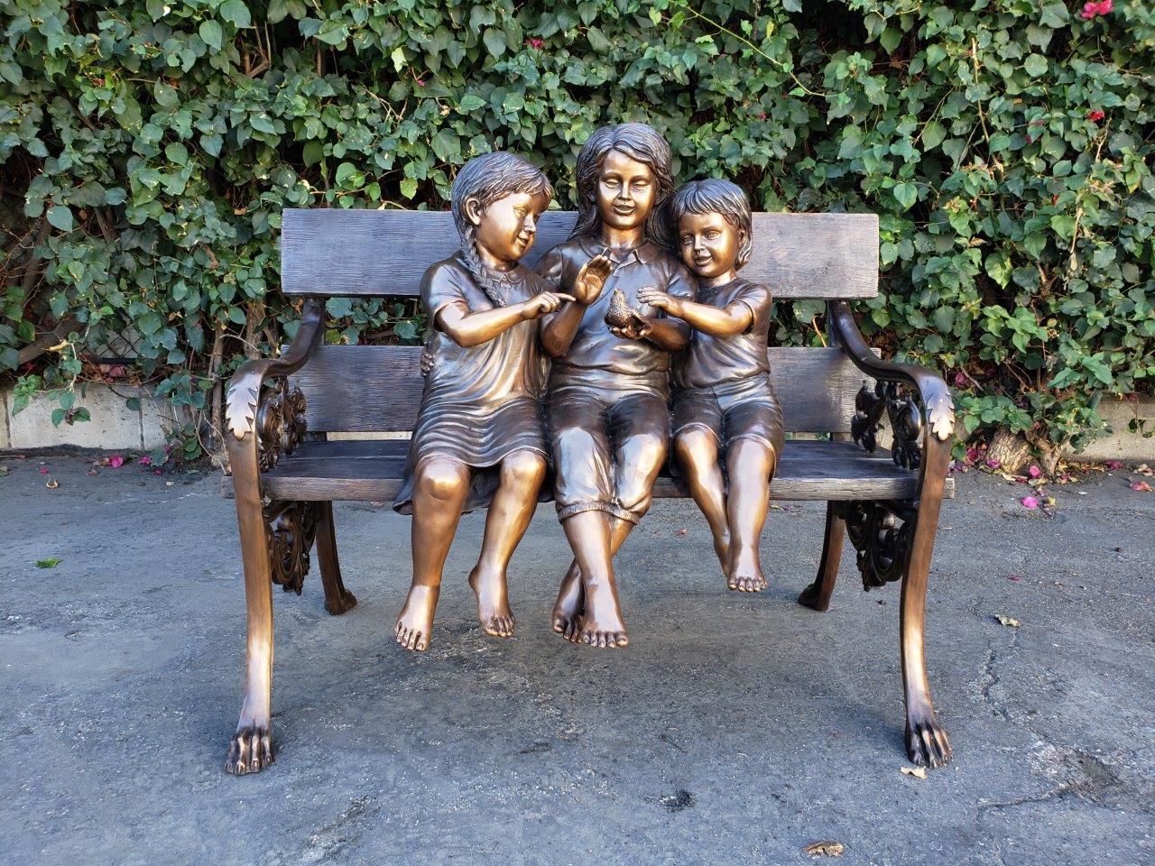 Three kids on a Bench Holding a Bird Bronze Statue - Size: 40"L x 30"W x 33"H.