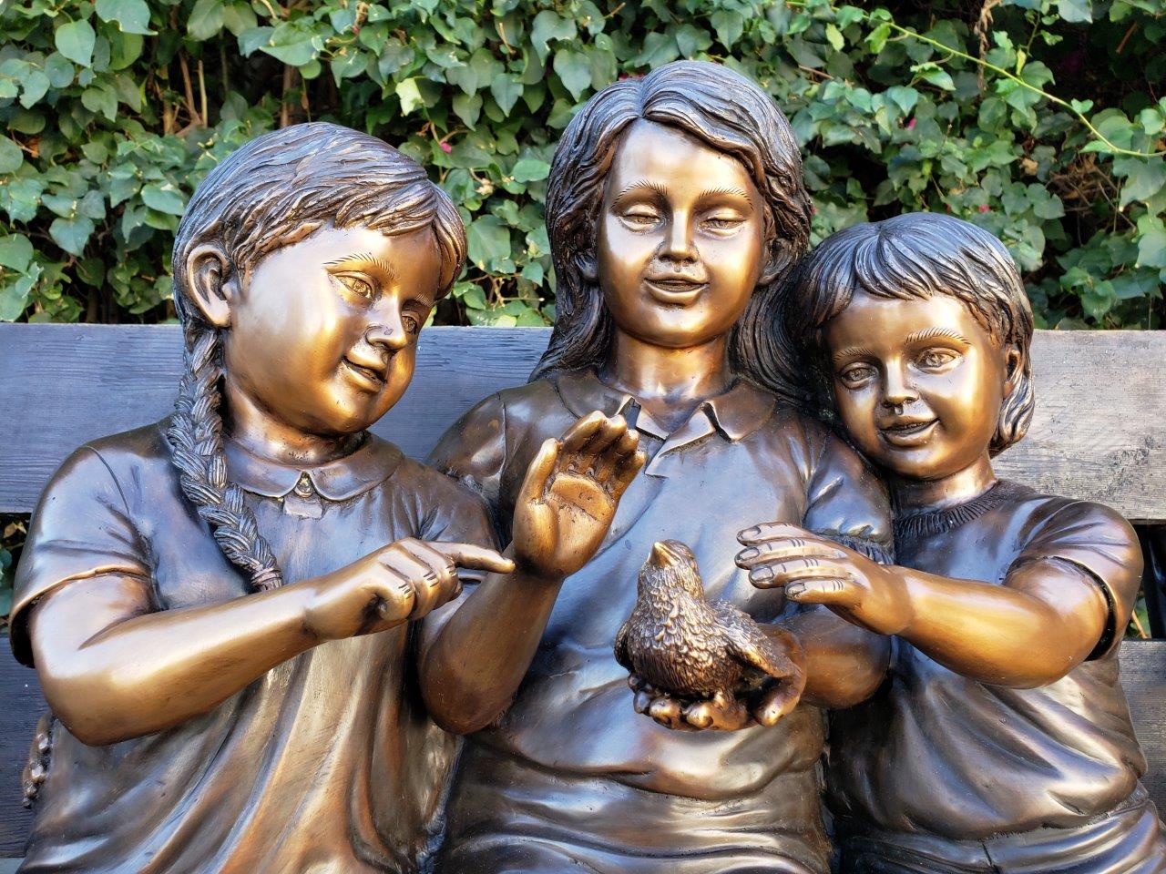 Three kids on a Bench Holding a Bird Bronze Statue - Size: 40"L x 30"W x 33"H.