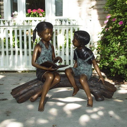 Boy and Girl on a tree log reading Bronze Statue -  Size: 37"L x 14"W x 27"H.