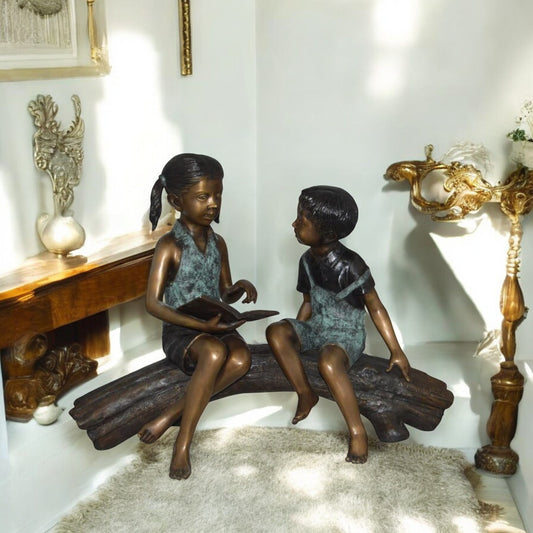 Boy and Girl on a tree log reading Bronze Statue -  Size: 37"L x 14"W x 27"H.