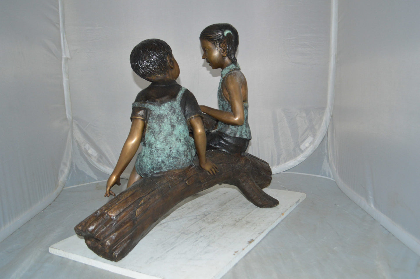 Boy and Girl on a tree log reading Bronze Statue - Size: 37"L x 14"W x 27"H.