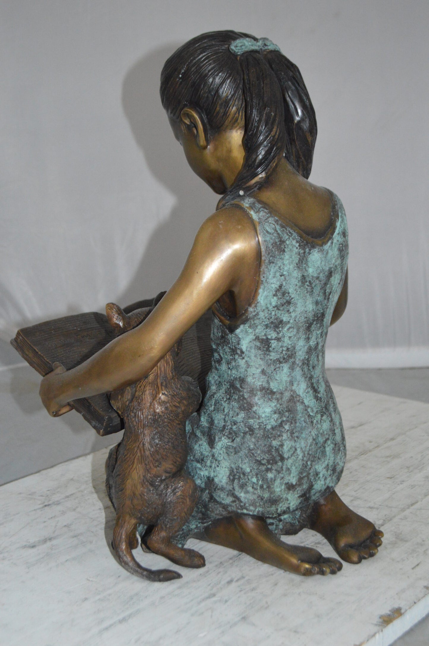 Girl and her dog reading a book Bronze Statue -  Size: 20"L x 8"W x 14"H.