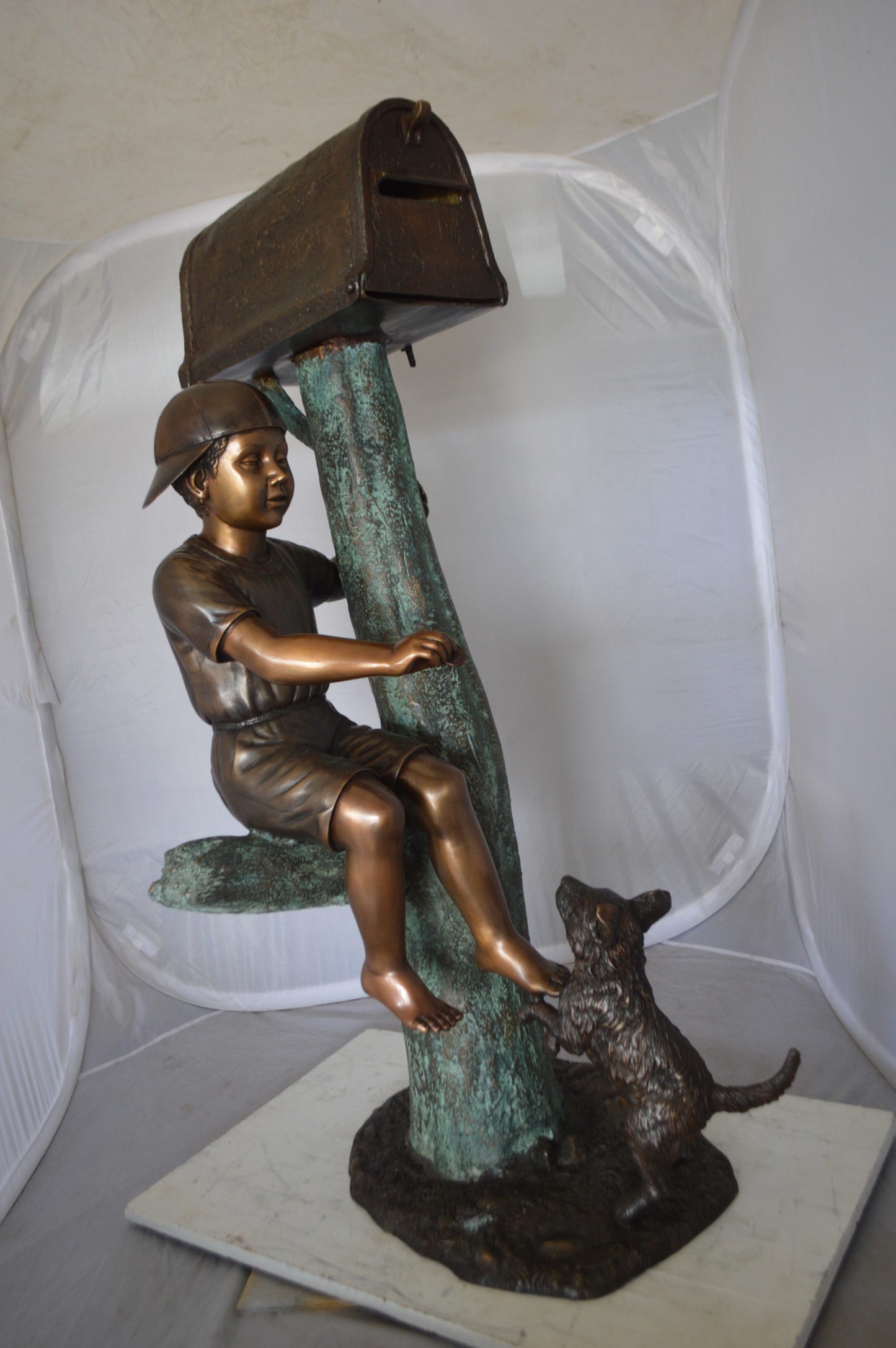 Boy Sitting on a Tree with Mailbox Bronze Statue - Size: 22"L x 23"W x 49"H.