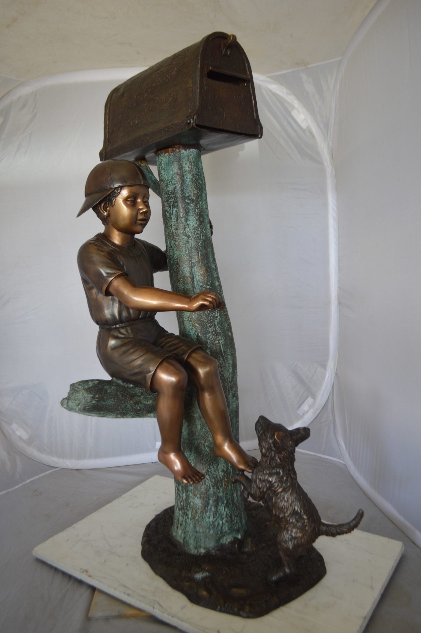 Boy Sitting on a Tree with Mailbox Bronze Statue - Size: 22"L x 23"W x 49"H.