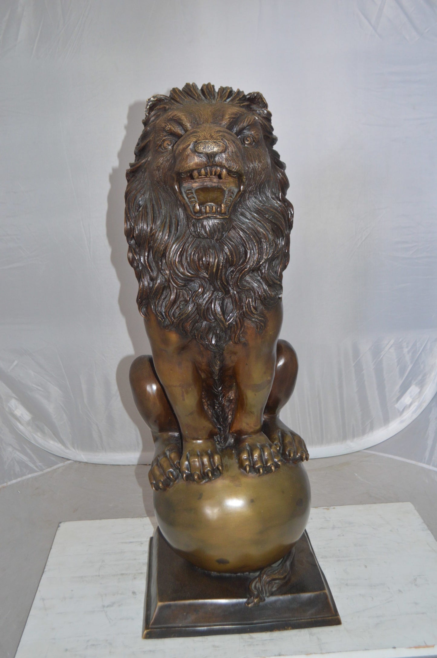 Pair of lions standing on balls, bronze statues - Size: 14"L x 16"W x 38"H.