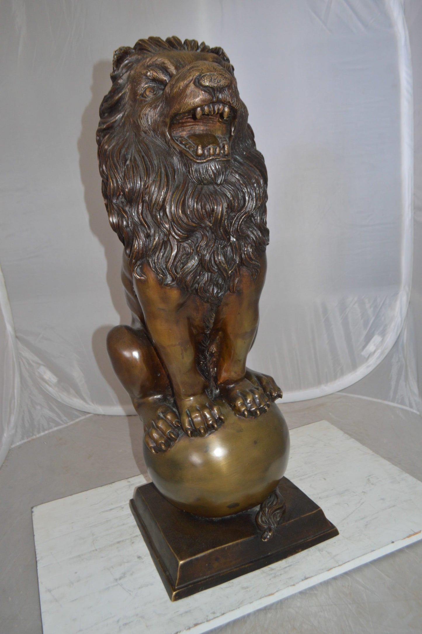 Pair of lions standing on balls, bronze statues - Size: 14"L x 16"W x 38"H.