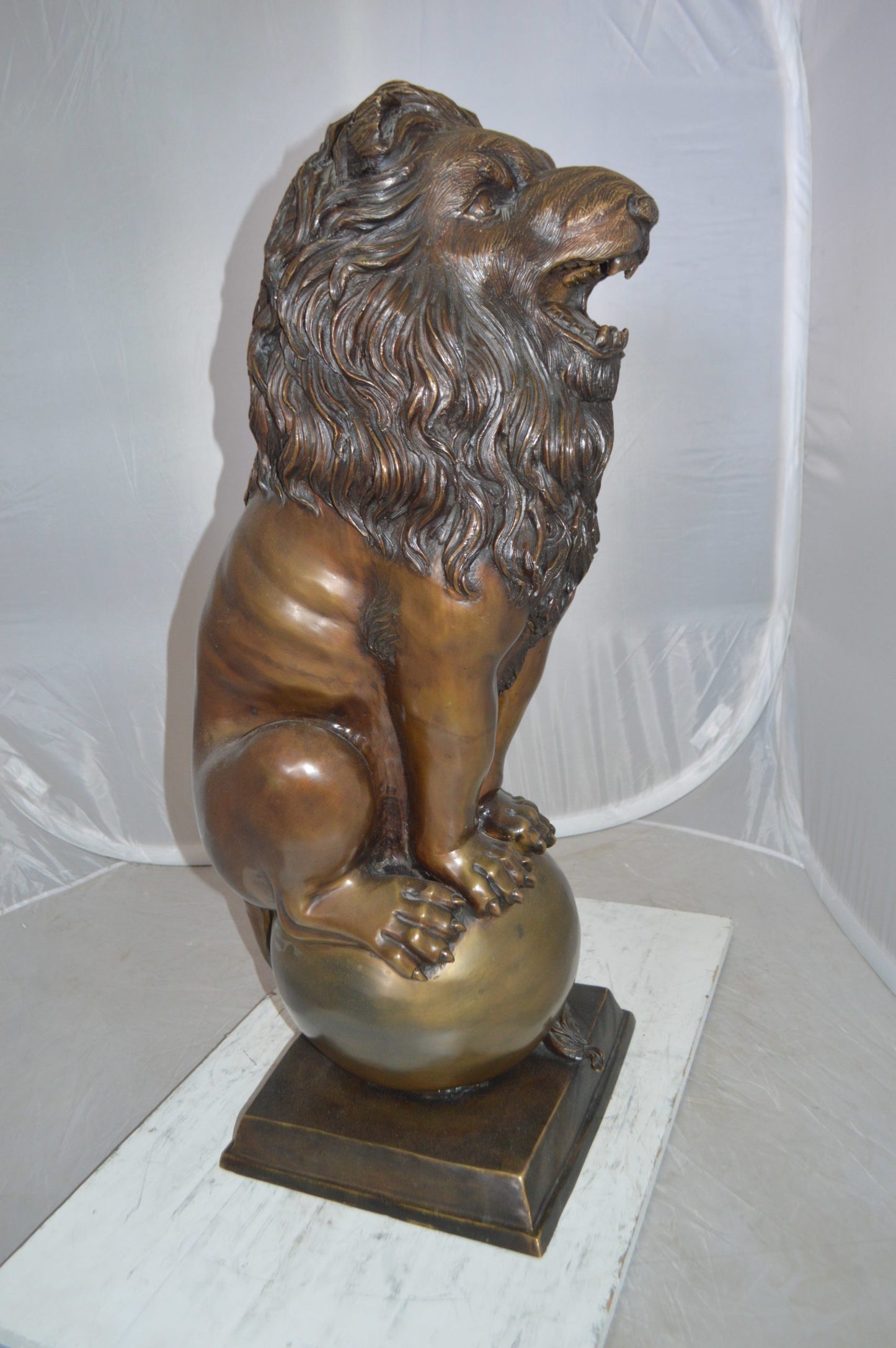 Pair of lions standing on balls, bronze statues - Size: 14"L x 16"W x 38"H.