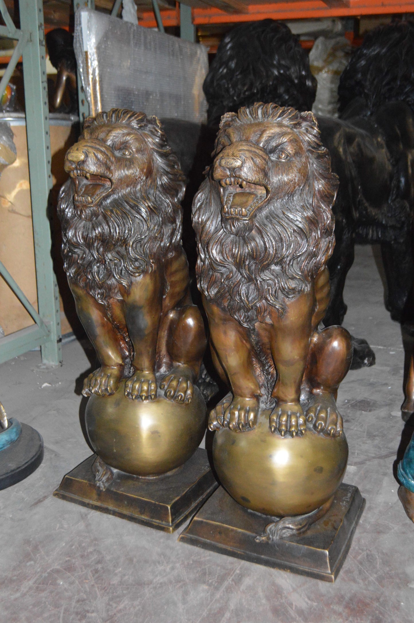 Pair of lions standing on balls, bronze statues - Size: 14"L x 16"W x 38"H.