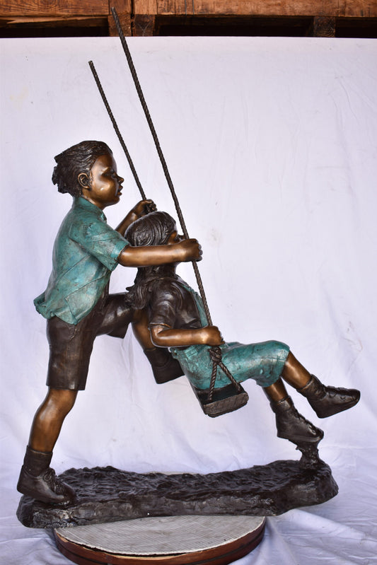 Boy and Girl Playing on a Swing bronze Statue - Size: 39"L x 17"W x 53"H.
