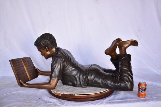 African American Boy reading a book bronze statue - Size: 42"L x 15"W x 19"H.