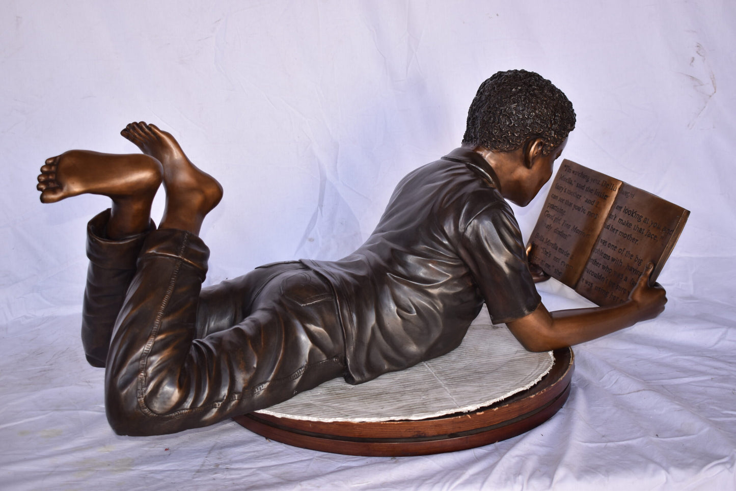 African American Boy reading a book bronze statue - Size: 42"L x 15"W x 19"H.