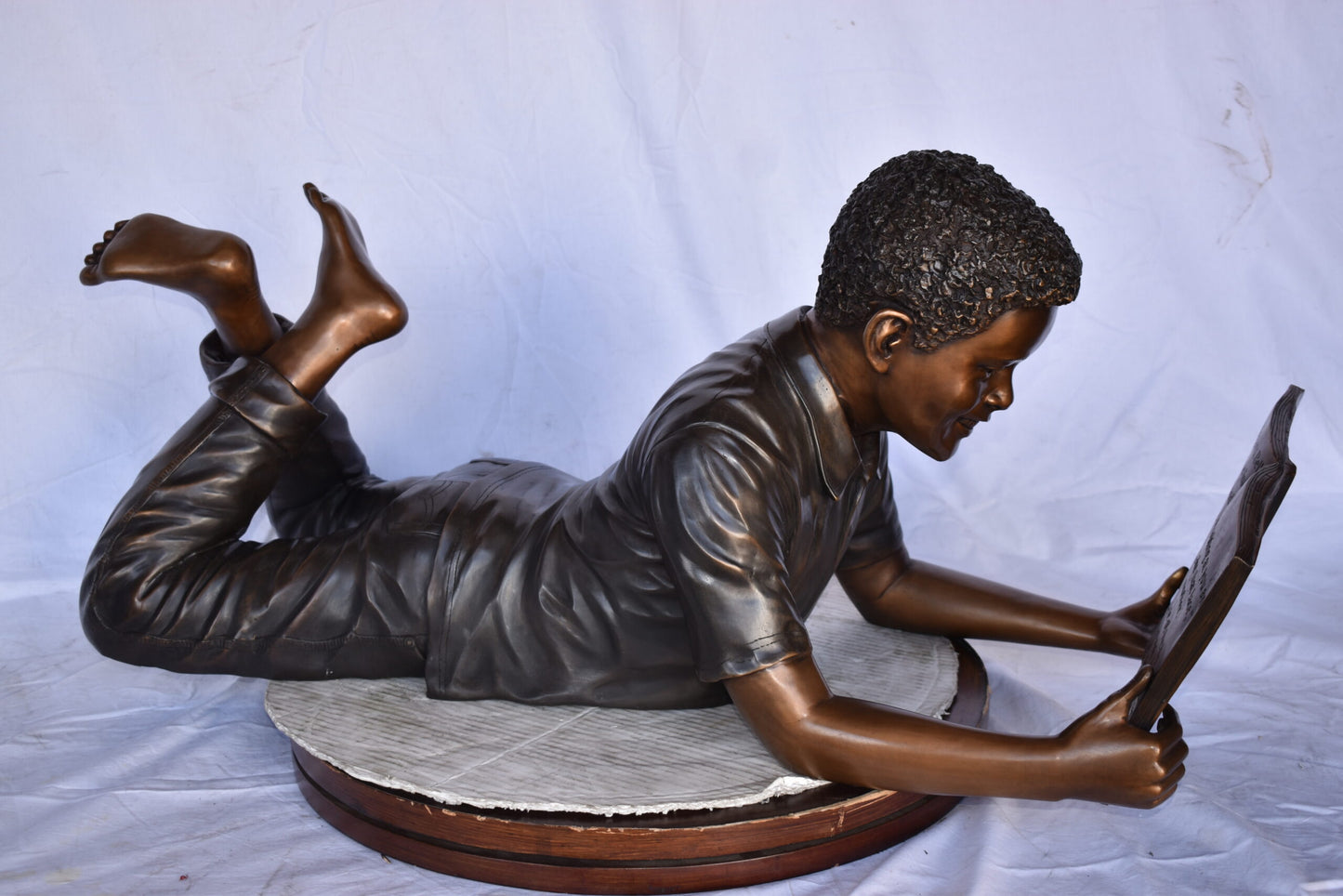African American Boy reading a book bronze statue - Size: 42"L x 15"W x 19"H.