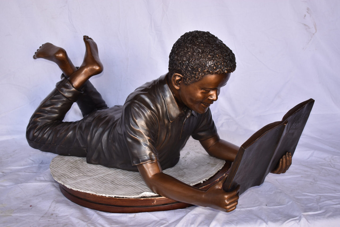 African American Boy reading a book bronze statue - Size: 42"L x 15"W x 19"H.