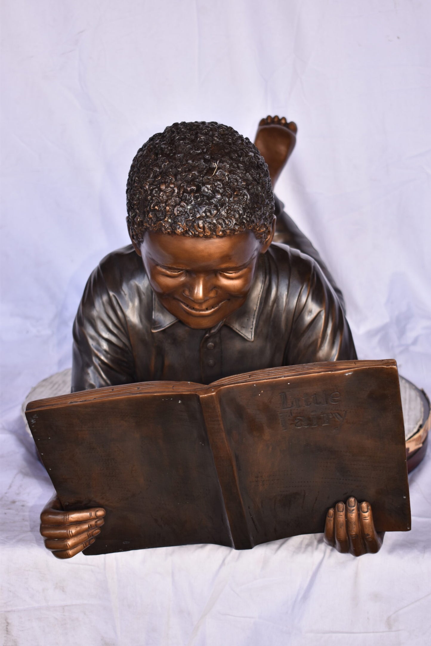 African American Boy reading a book bronze statue - Size: 42"L x 15"W x 19"H.
