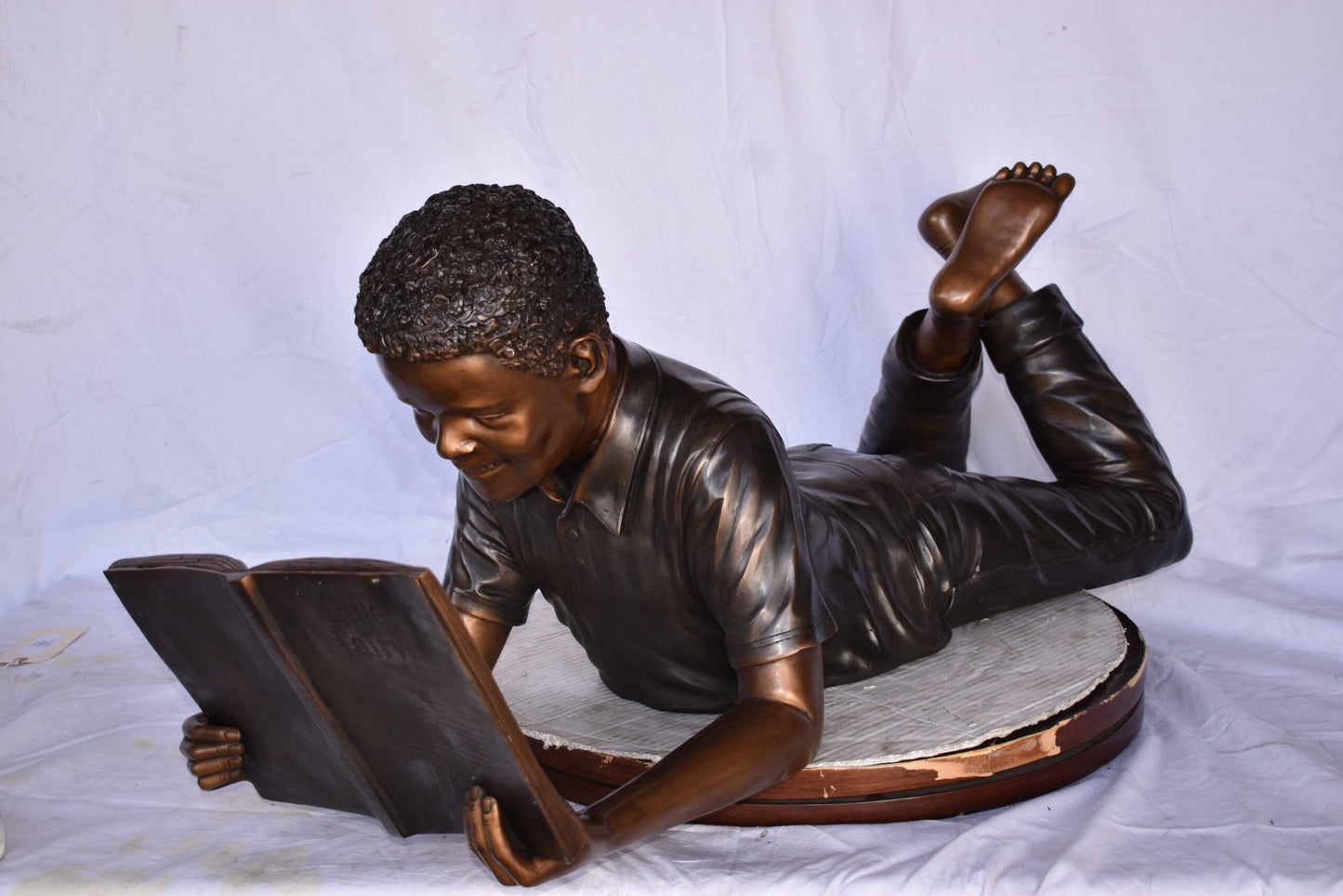 African American Boy reading a book bronze statue - Size: 42"L x 15"W x 19"H.