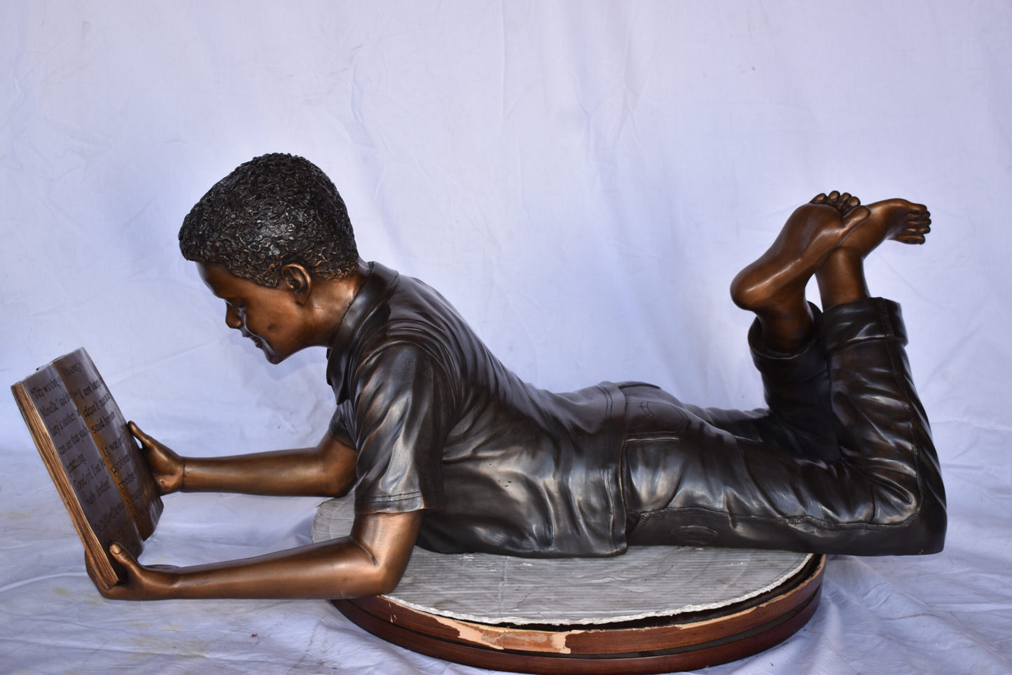 African American Boy reading a book bronze statue - Size: 42"L x 15"W x 19"H.