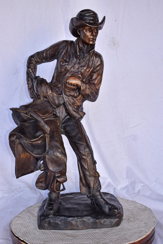 Cowboy Holding His Saddle Bronze Statue - Size: 20"L x 14"W x 35"H.