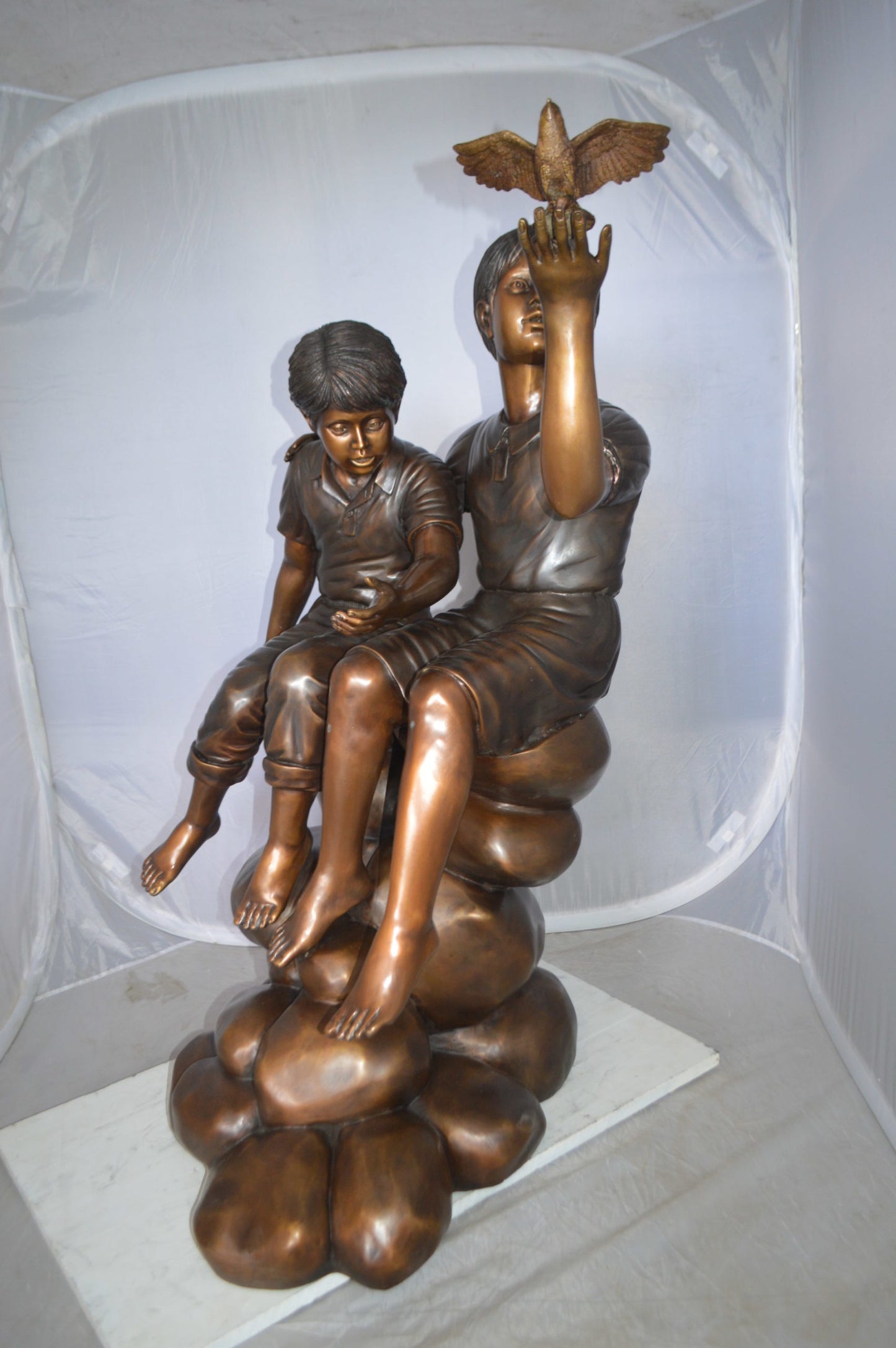 Two Kids on Rocks with a Bird Bronze Statue - Size: 36"L x 30"W x 44"H.