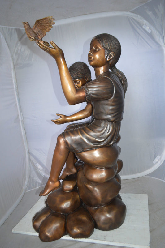 Two Kids on Rocks with a Bird Bronze Statue - Size: 36"L x 30"W x 44"H.