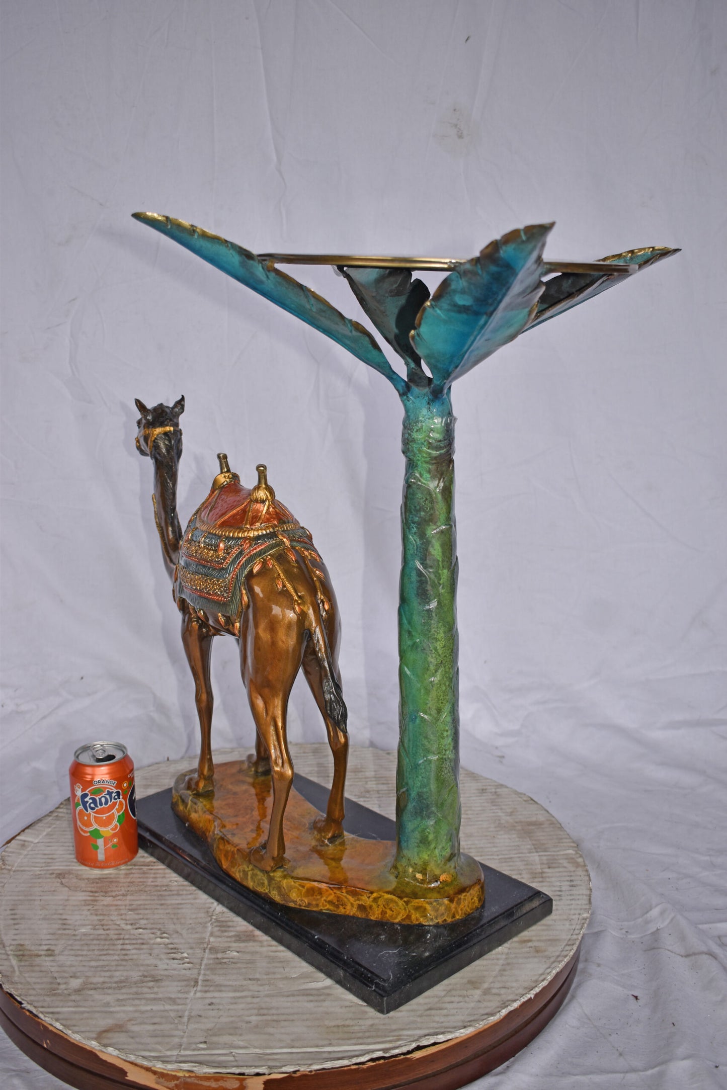 Camel Standing Under A Palm Tree Bronze Statue - Size: 20"L x 29"W x 25"H.
