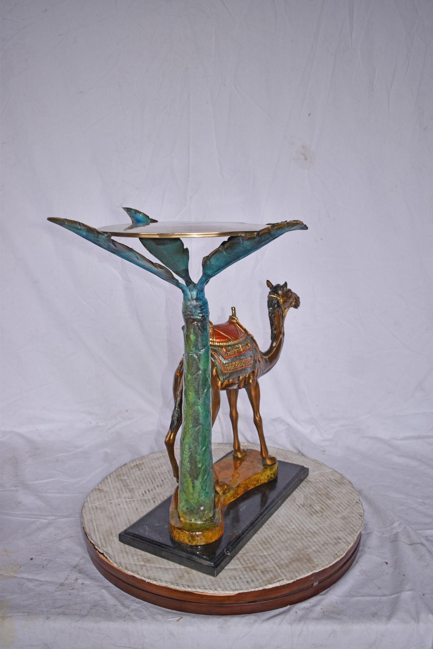 Camel Standing Under A Palm Tree Bronze Statue - Size: 20"L x 29"W x 25"H.