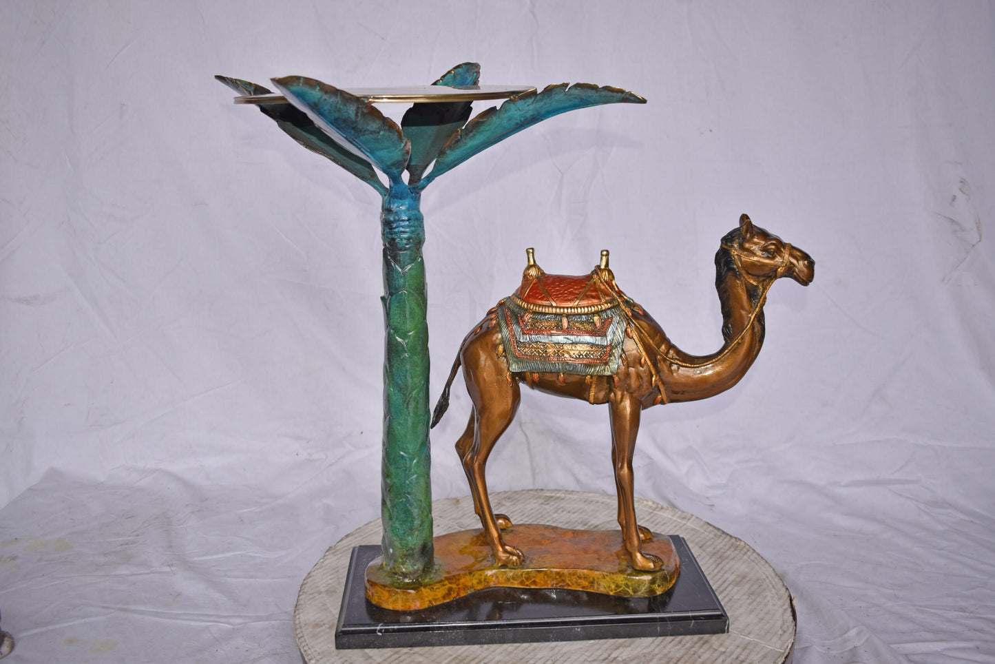 Camel Standing Under A Palm Tree Bronze Statue - Size: 20"L x 29"W x 25"H.