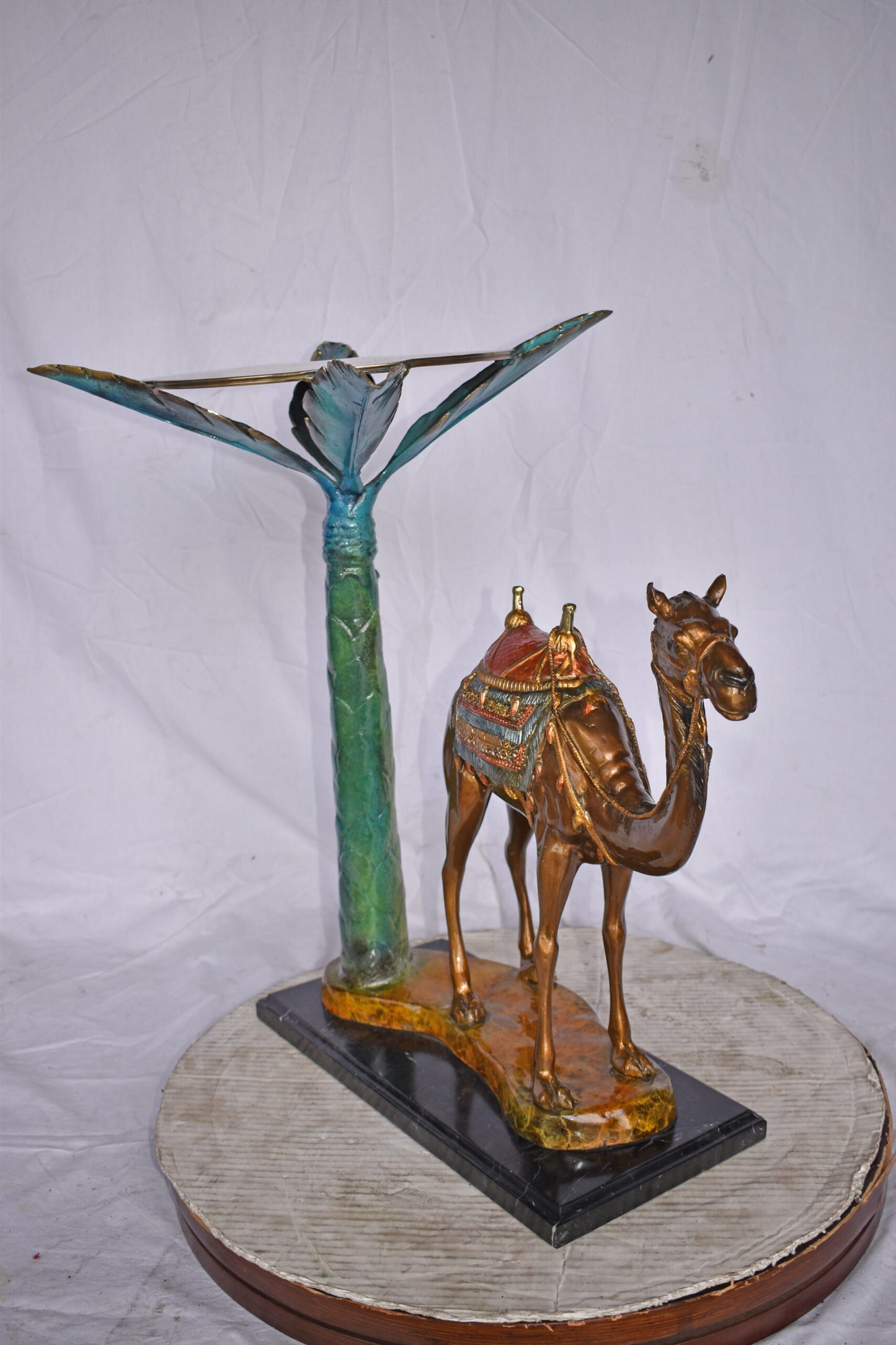 Camel Standing Under A Palm Tree Bronze Statue - Size: 20"L x 29"W x 25"H.