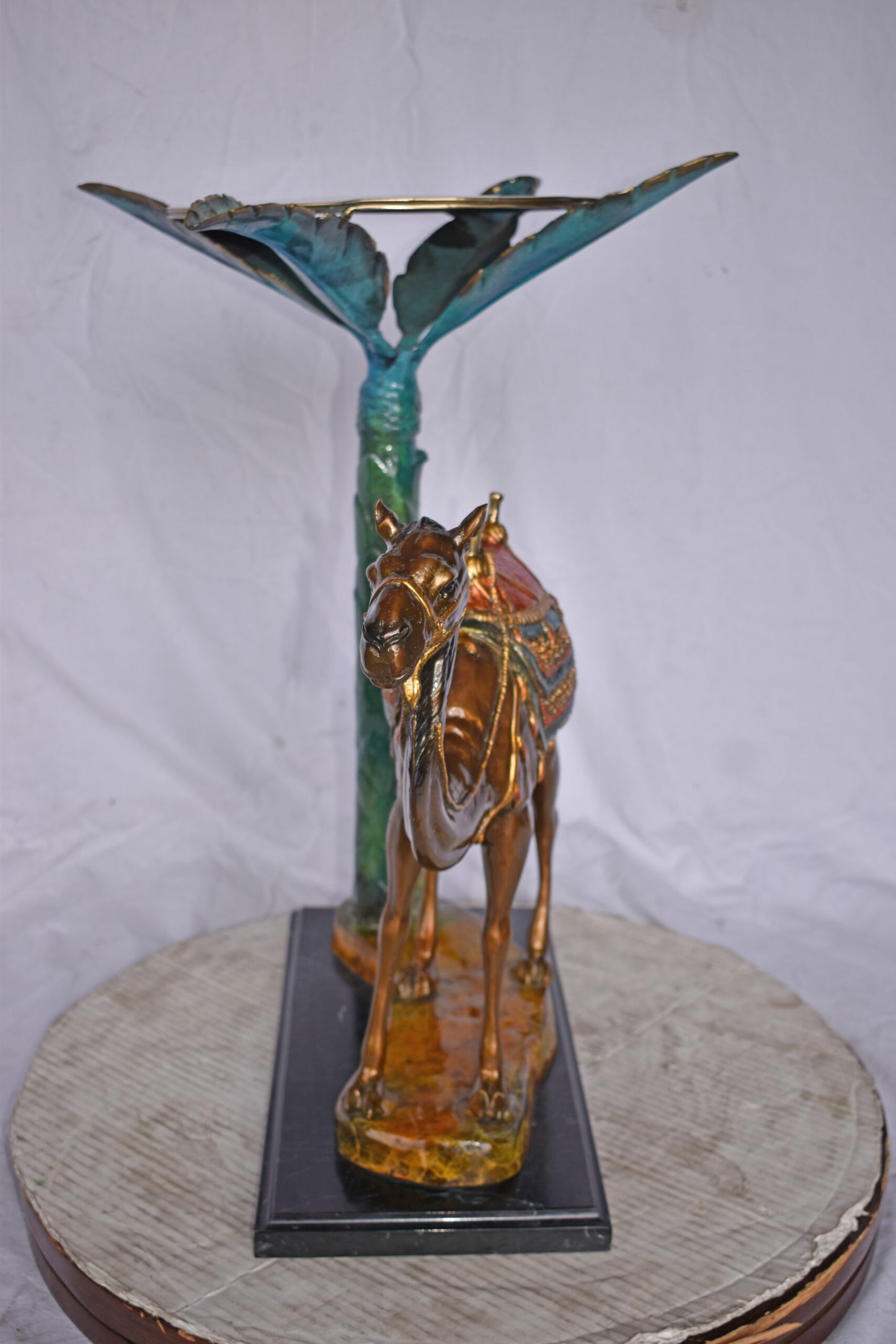 Camel Standing Under A Palm Tree Bronze Statue - Size: 20"L x 29"W x 25"H.