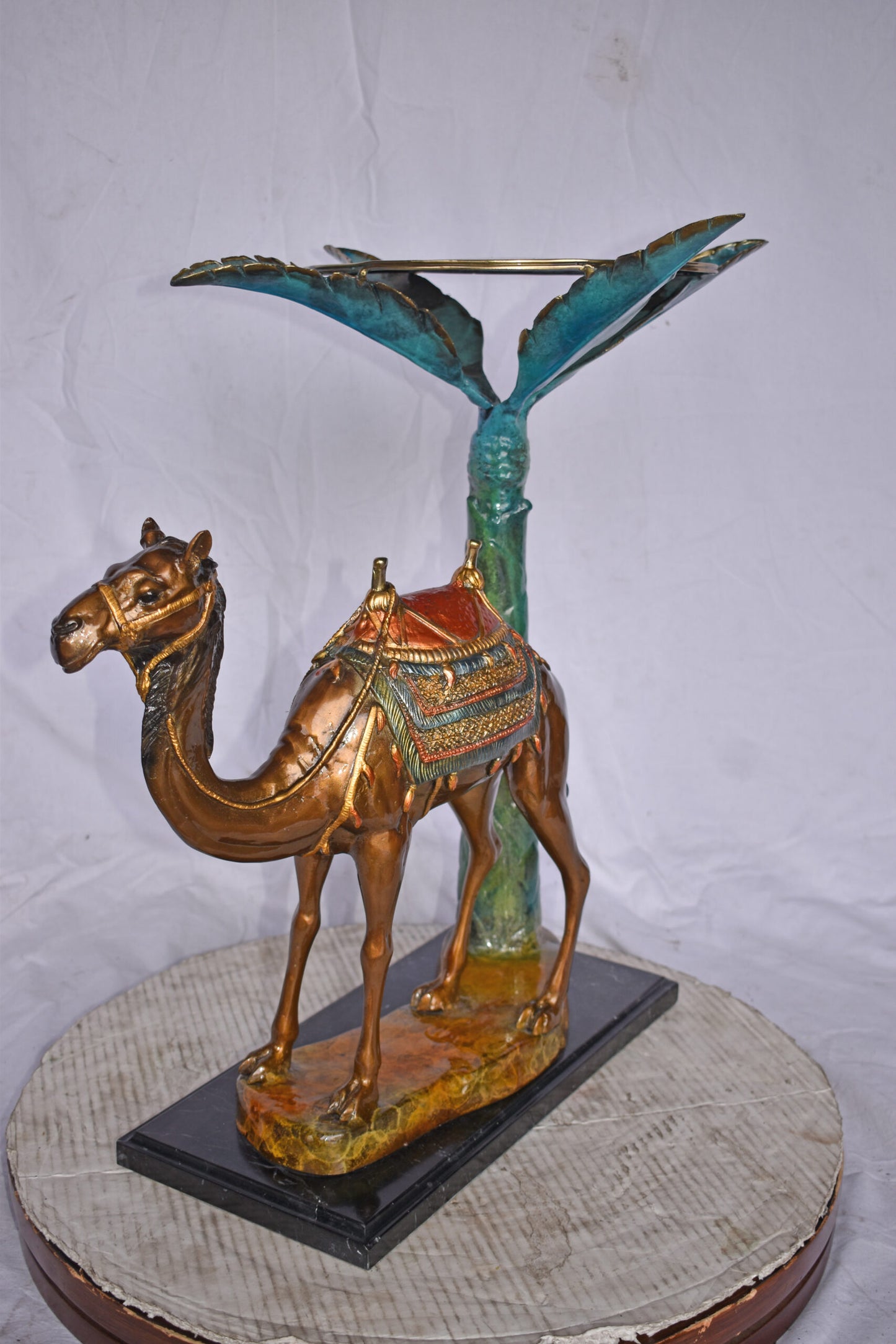 Camel Standing Under A Palm Tree Bronze Statue - Size: 20"L x 29"W x 25"H.