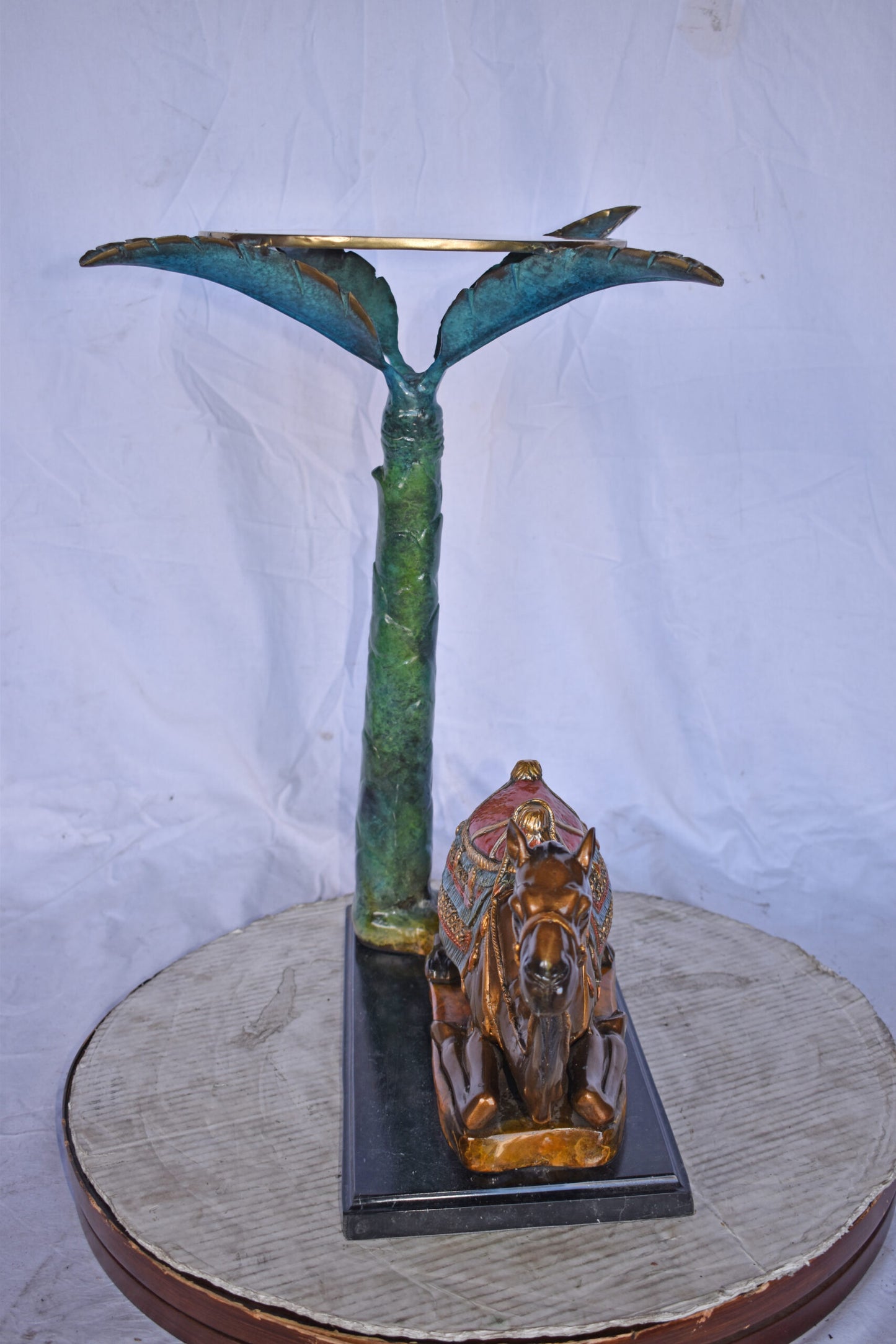Camel Sitting Under A Palm Tree Bronze Statue - Size: 17"L x 27"W x 23"H.