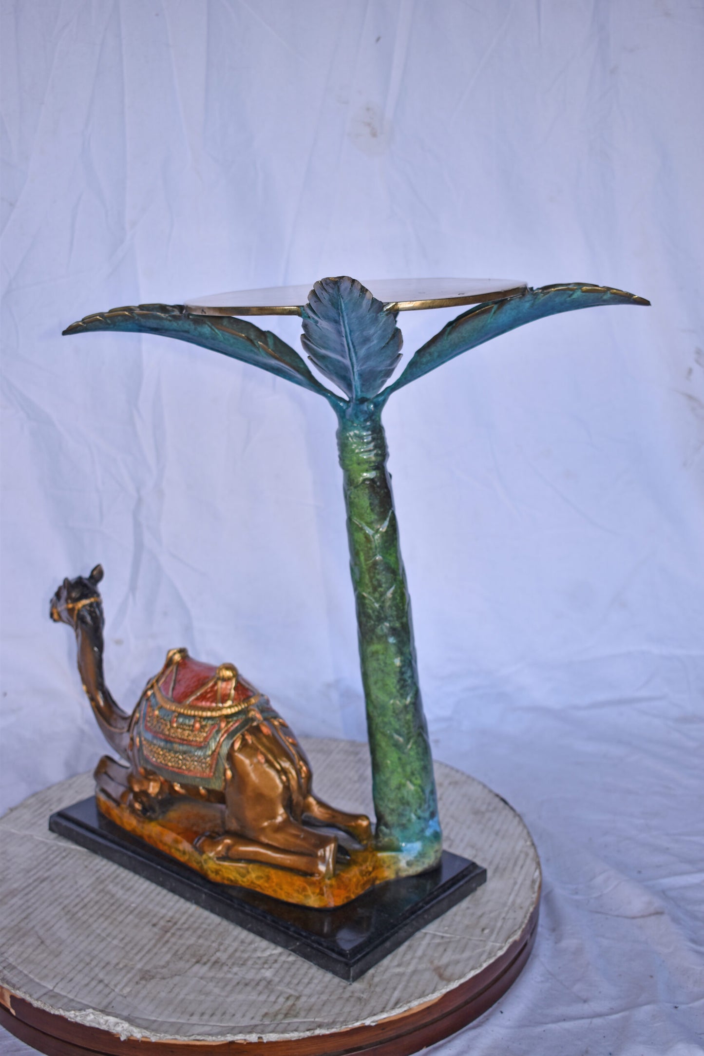 Camel Sitting Under A Palm Tree Bronze Statue - Size: 17"L x 27"W x 23"H.