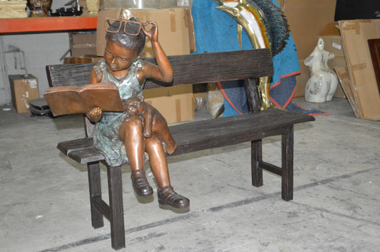 Girl with Glasses on Bench Bronze Statue - Size: 43"L x 20"W x 36"H.