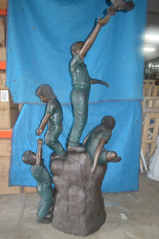 Four Kids Playing on a Rock Bronze Statue -  Size: 49"L x 26"W x 89"H.
