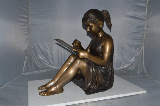 Girl reading from a notebook Bronze Statue - Size: 26"L x 16"W x 25"H.