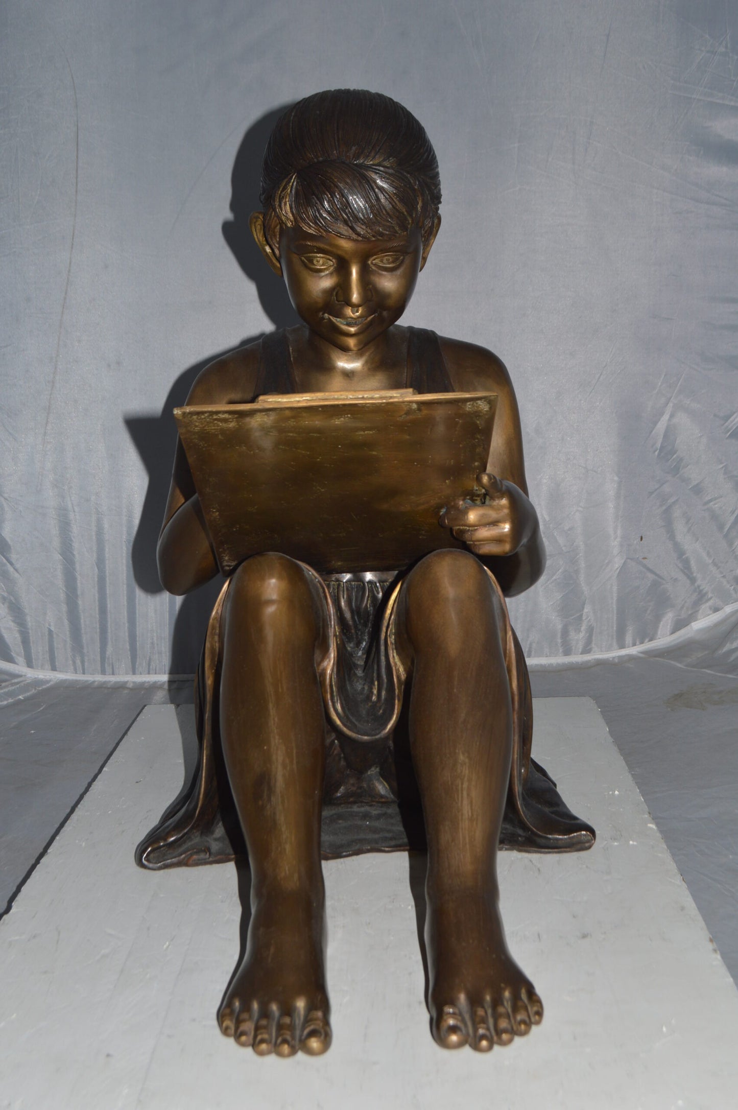 Girl reading from a notebook Bronze Statue - Size: 26"L x 16"W x 25"H.
