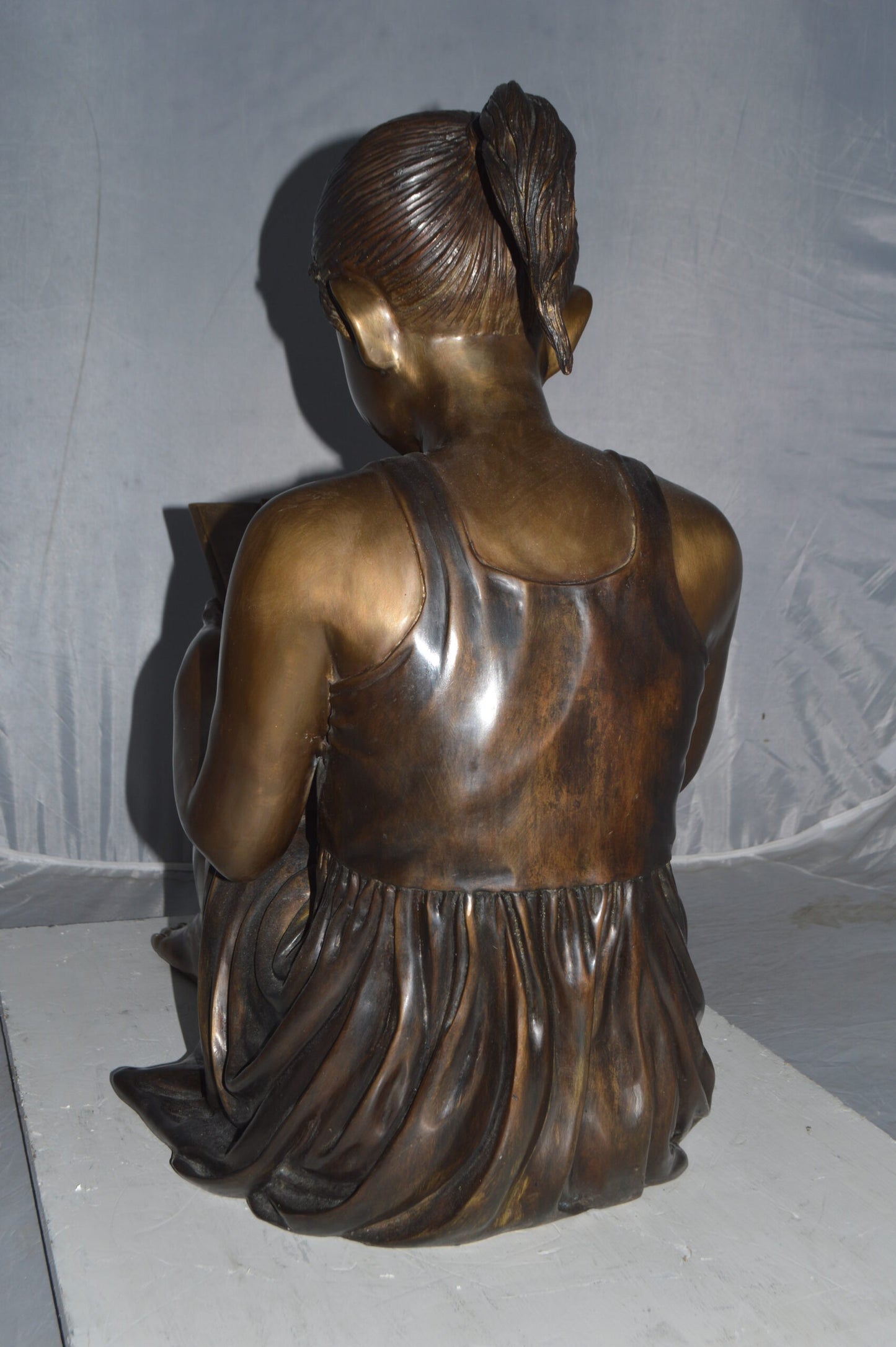 Girl reading from a notebook Bronze Statue - Size: 26"L x 16"W x 25"H.