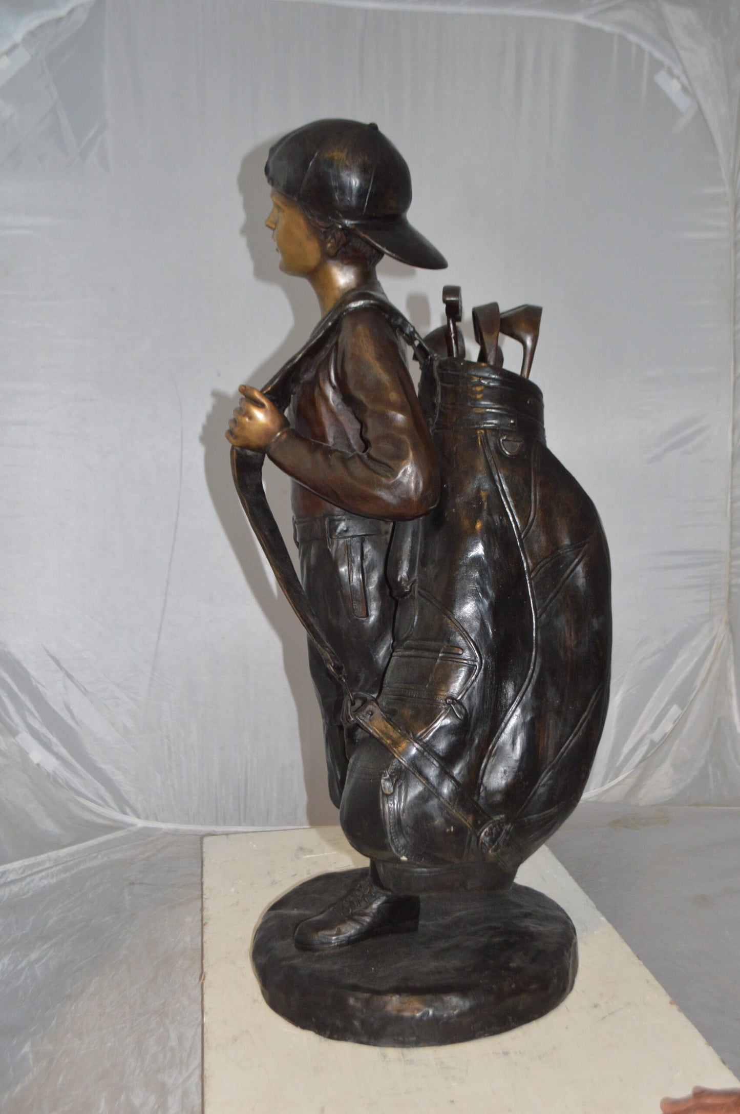 Boy Carrying A Golf Bag Bronze Statue - Size: 15"L x 15"W x 38"H.