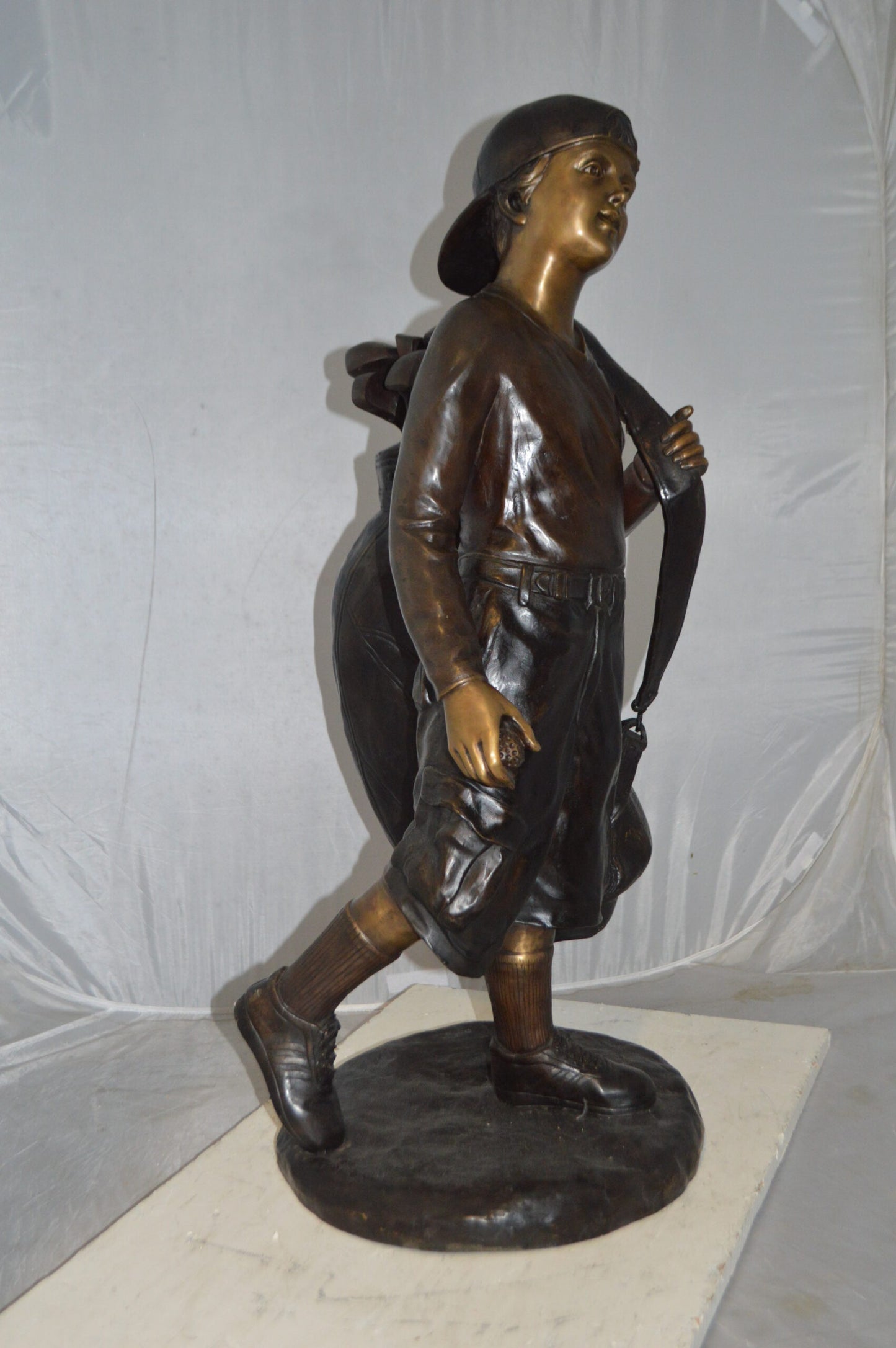 Boy Carrying A Golf Bag Bronze Statue - Size: 15"L x 15"W x 38"H.