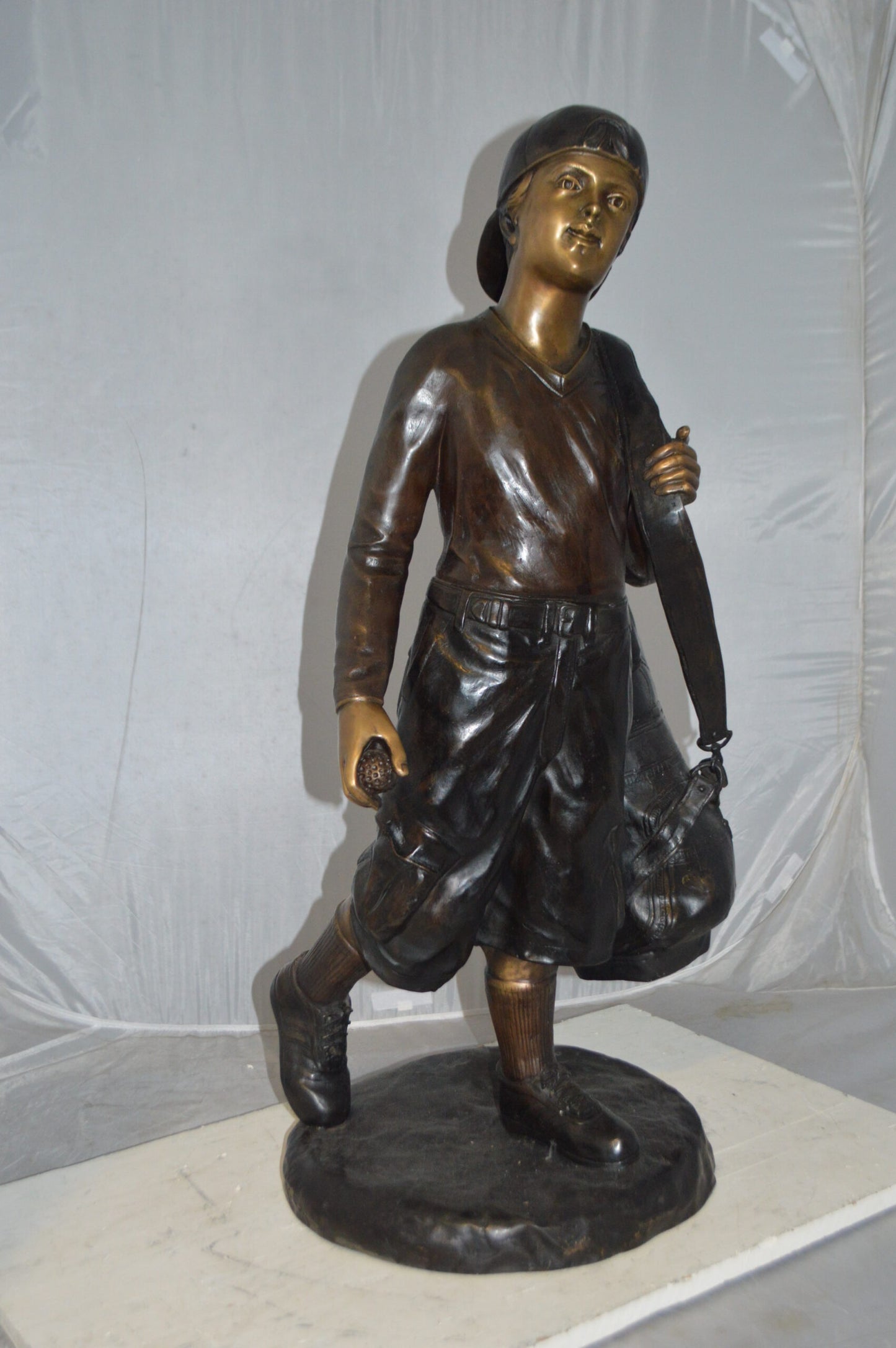 Boy Carrying A Golf Bag Bronze Statue - Size: 15"L x 15"W x 38"H.