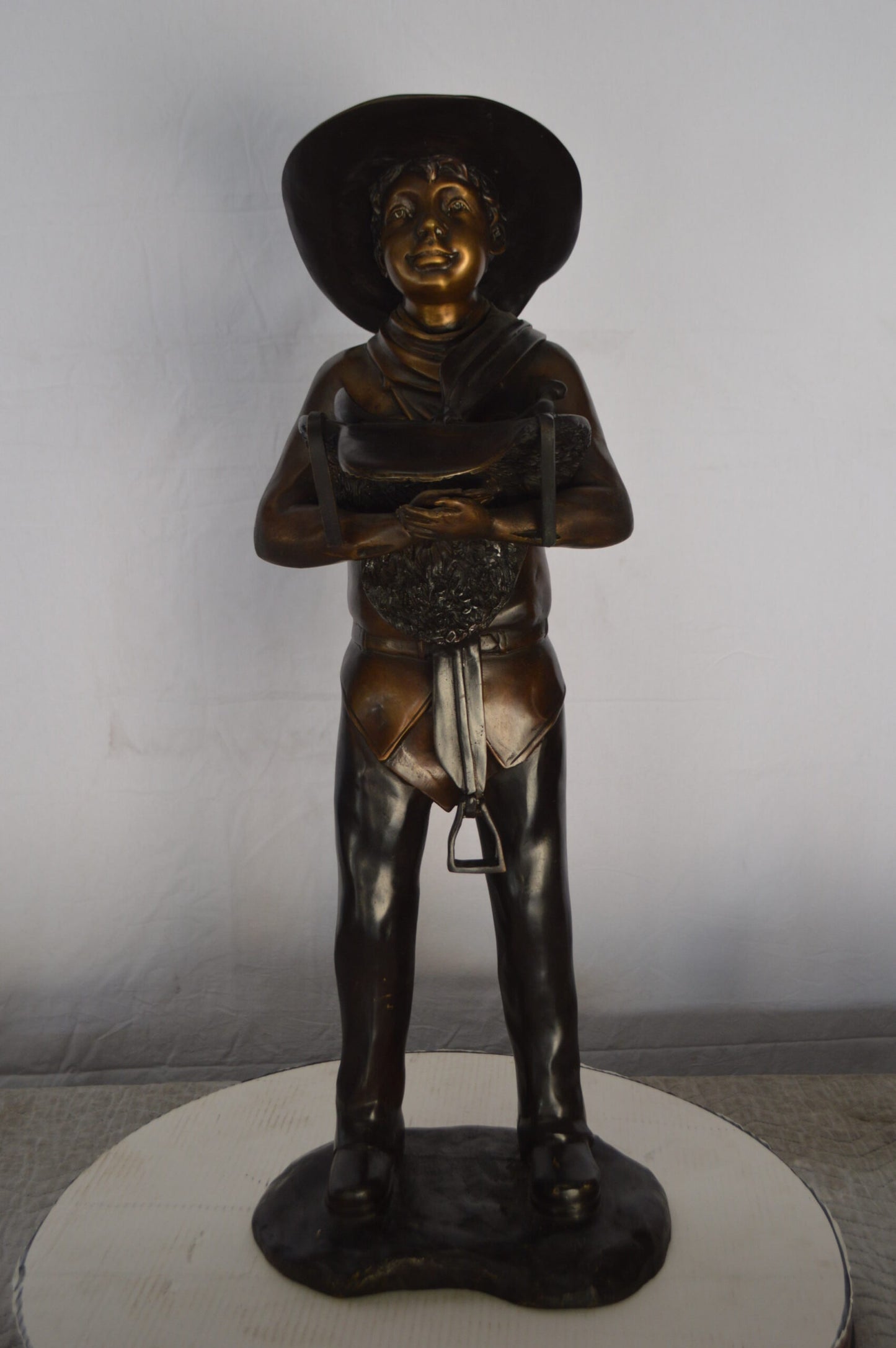 Cowboy Holding a Saddle Bronze Statue  -  Size: 12"L x 11"W x 32"H.