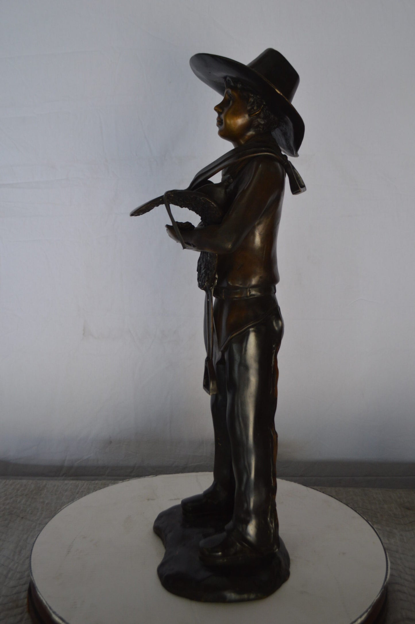 Cowboy Holding a Saddle Bronze Statue  -  Size: 12"L x 11"W x 32"H.