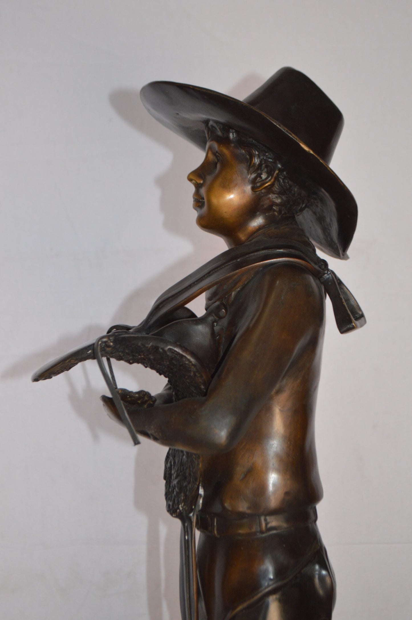 Cowboy Holding a Saddle Bronze Statue  -  Size: 12"L x 11"W x 32"H.