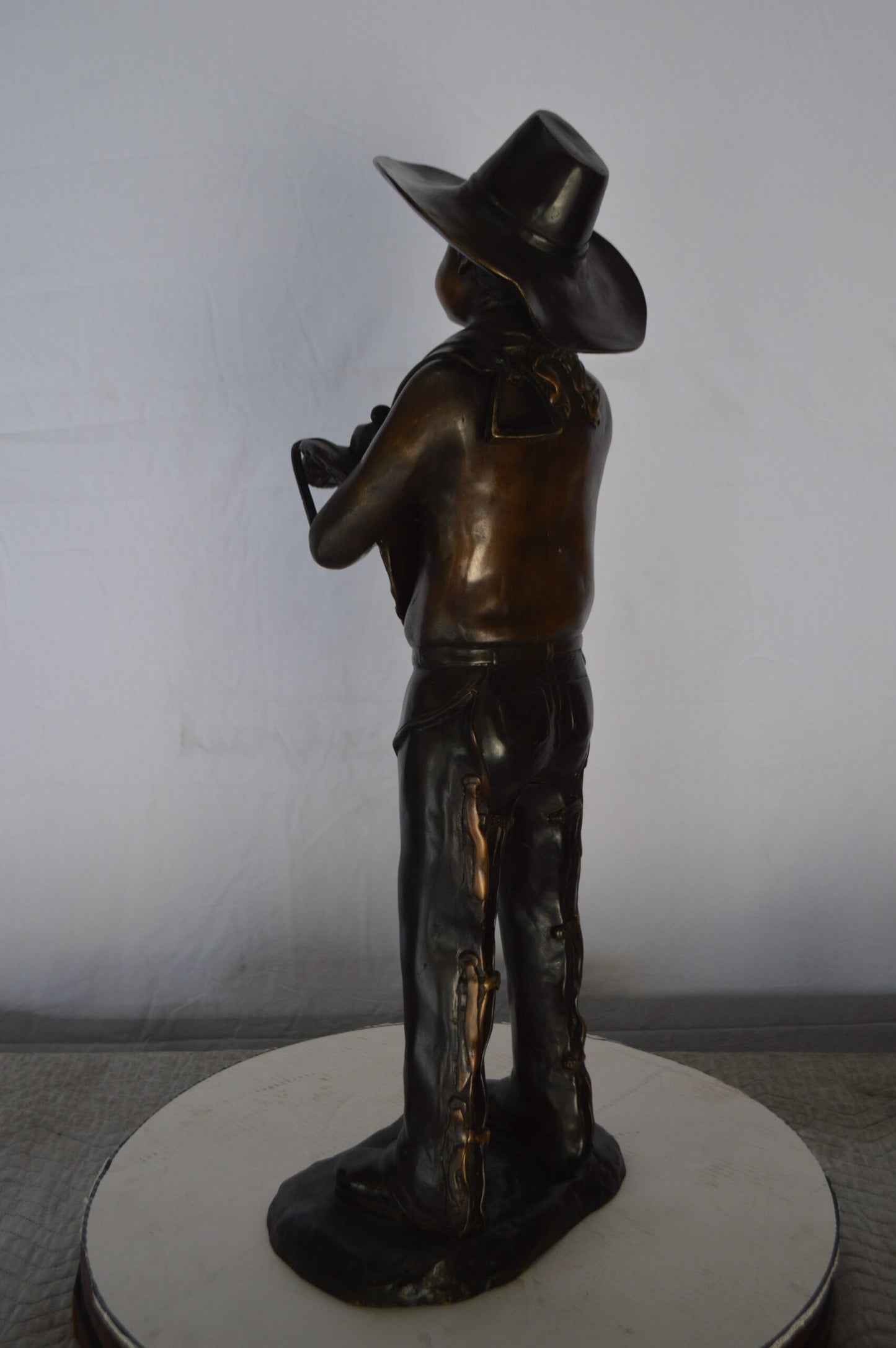 Cowboy Holding a Saddle Bronze Statue  -  Size: 12"L x 11"W x 32"H.