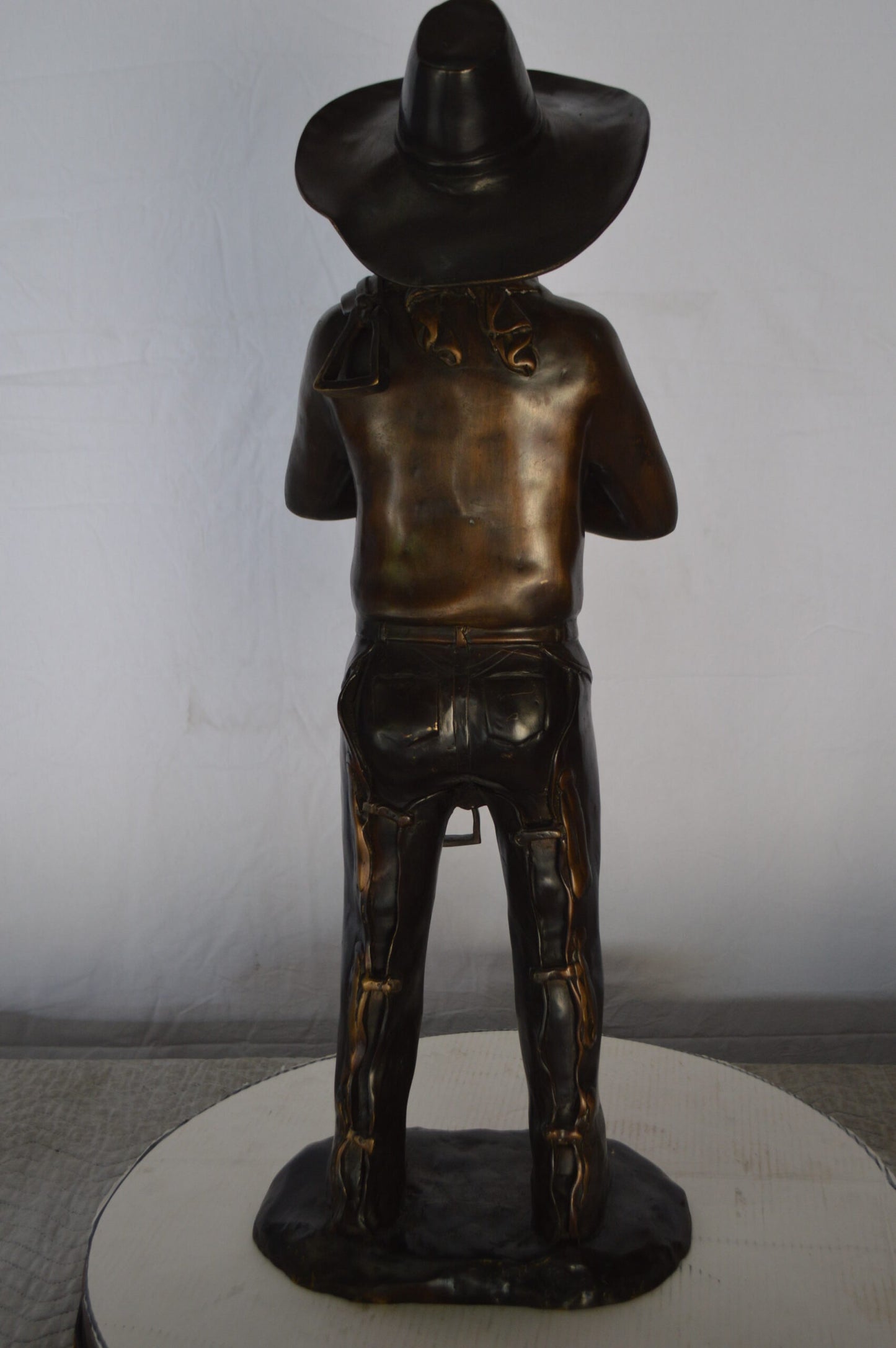 Cowboy Holding a Saddle Bronze Statue  -  Size: 12"L x 11"W x 32"H.