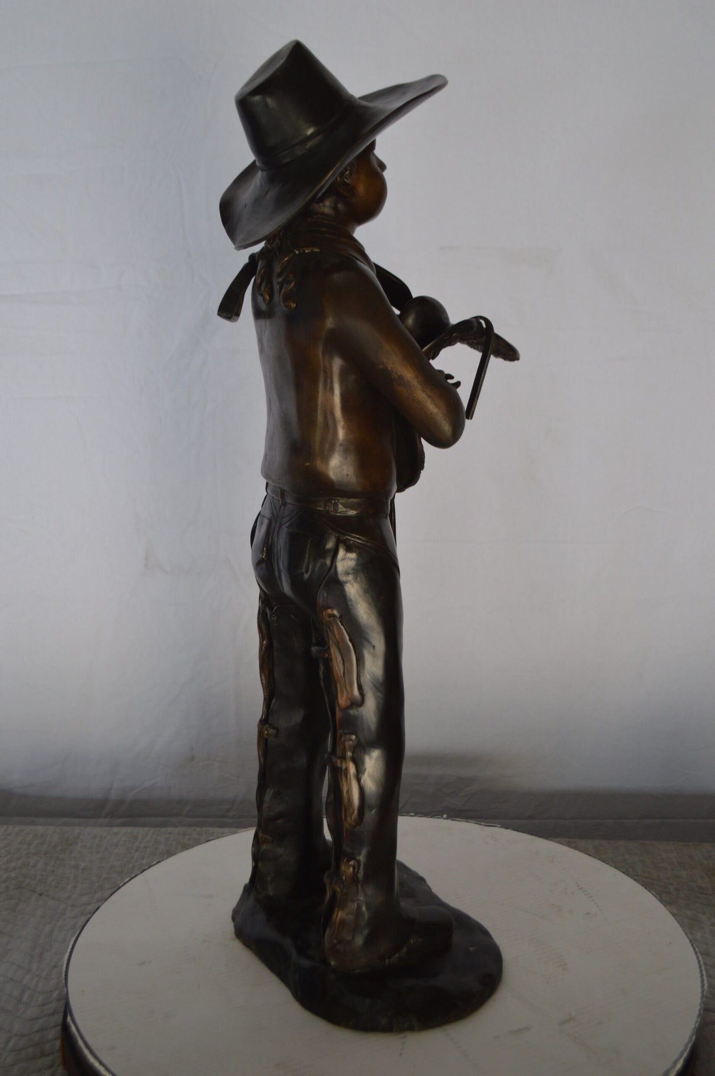 Cowboy Holding a Saddle Bronze Statue  -  Size: 12"L x 11"W x 32"H.