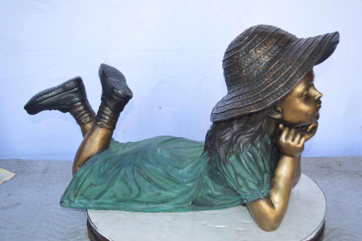 Girl Wearing A Hat Lying on Stomach Bronze Statue -  Size: 33"L x 17"W x 17"H.