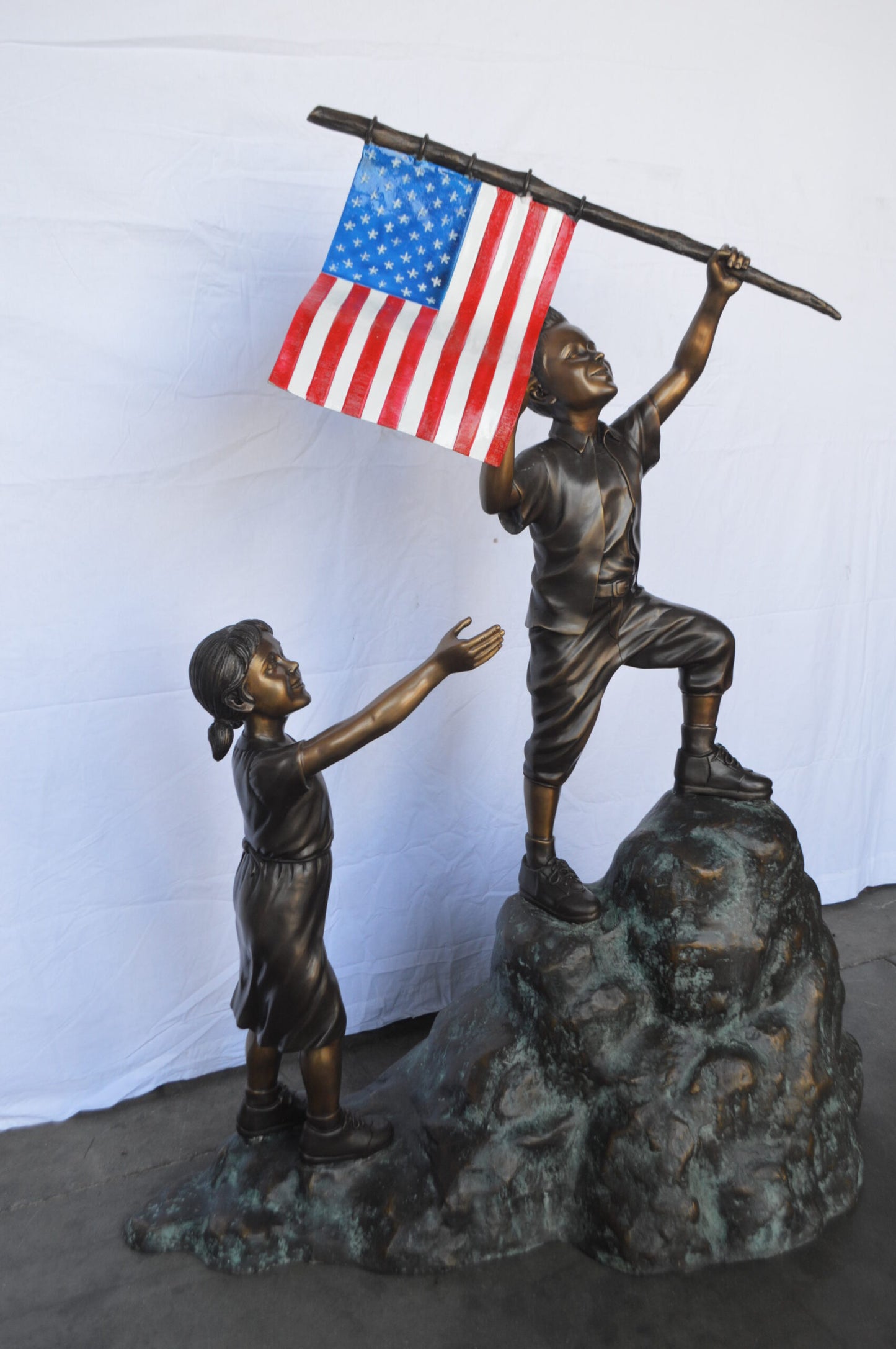Two Kids on Rock W the American Flag Bronze Statue - Size: 50"L x 22"W x 58"H.