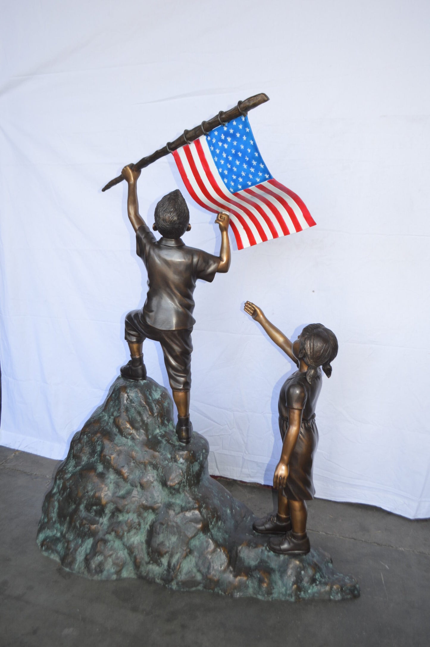 Two Kids on Rock W the American Flag Bronze Statue - Size: 50"L x 22"W x 58"H.