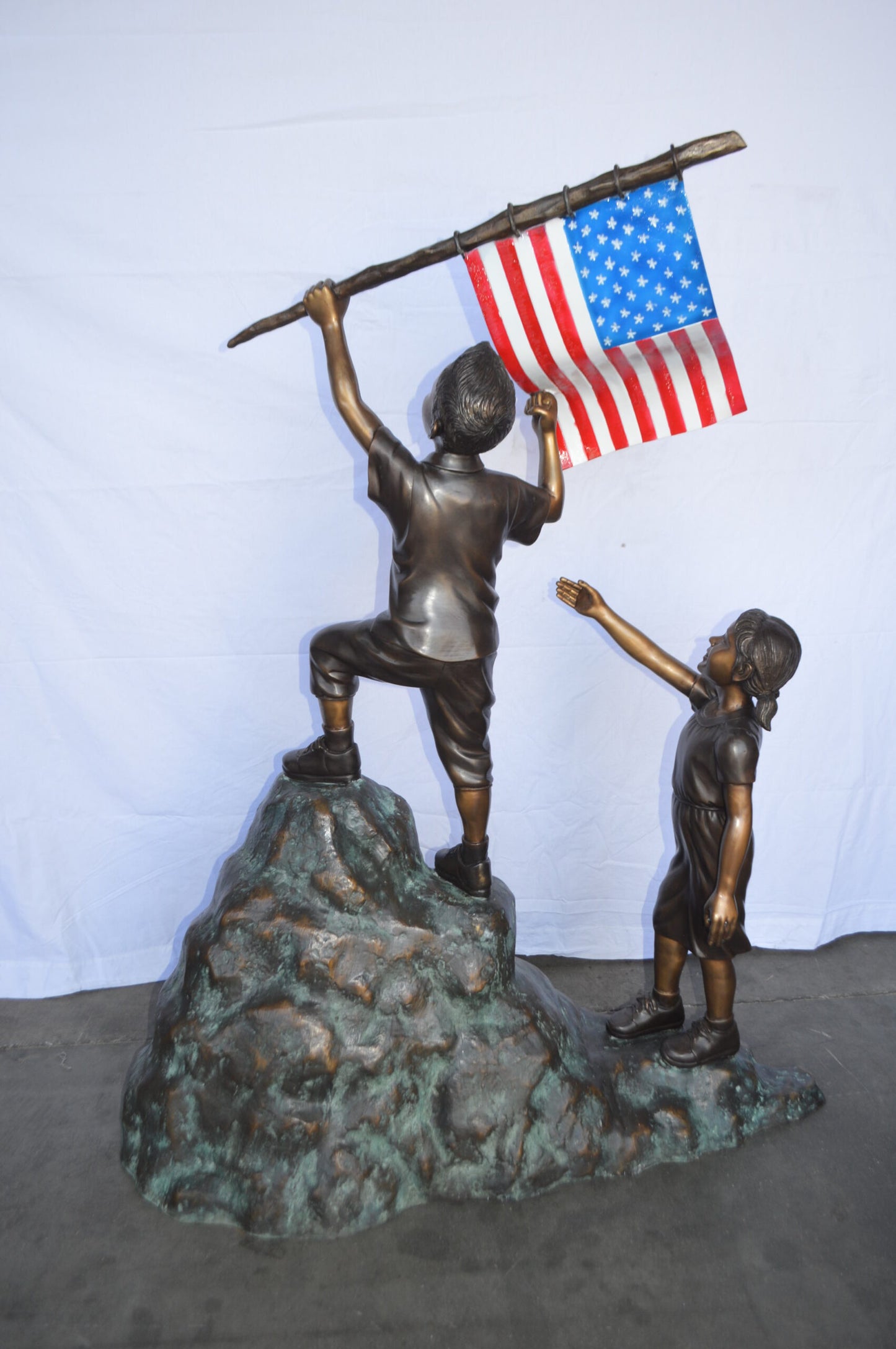 Two Kids on Rock W the American Flag Bronze Statue - Size: 50"L x 22"W x 58"H.