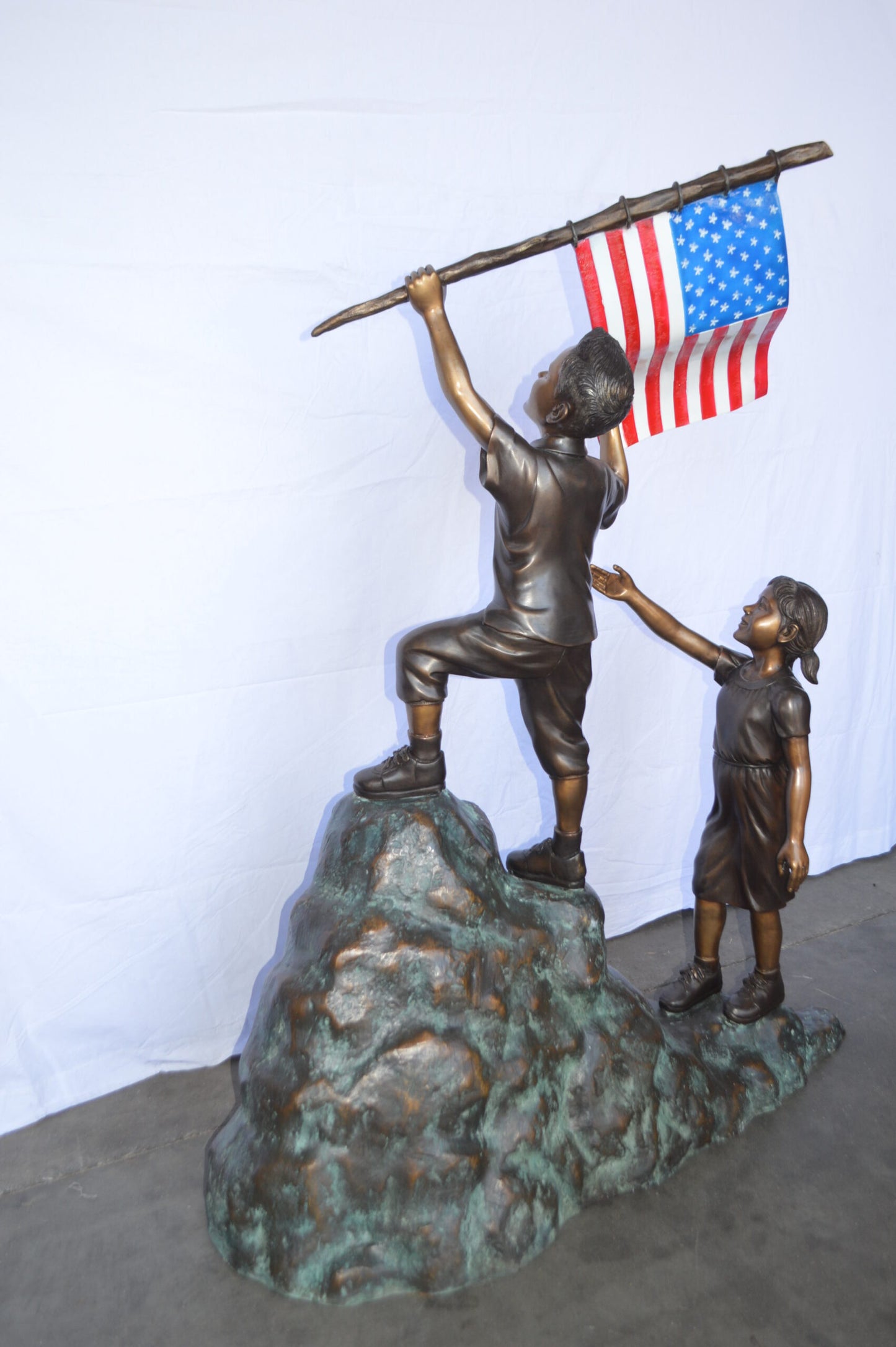 Two Kids on Rock W the American Flag Bronze Statue -  Size: 50"L x 22"W x 58"H.
